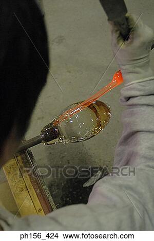 High angle view of a person blowing molten glass with a blow pipe View Large Photo Image Picture - High angle view of a person blowing molten glass with a blow pipe. Fotosearch