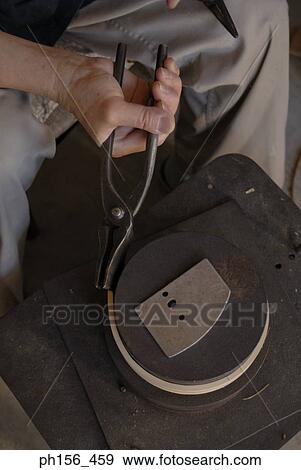 Stock Photo - High angle view of a person's hand bending a wooden strip with the help of a pair of pliers. Fotosearch