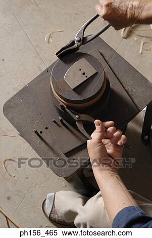 Stock Photography - High angle view of a person's hands bending a wooden strip with the help of a pair of pliers. Fotosearch