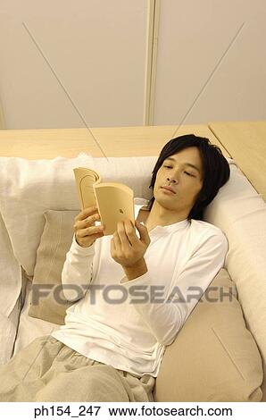High angle view of a young man reading a book View Large Photo Image Stock Photo - High angle view of a young man reading a book. Fotosearch