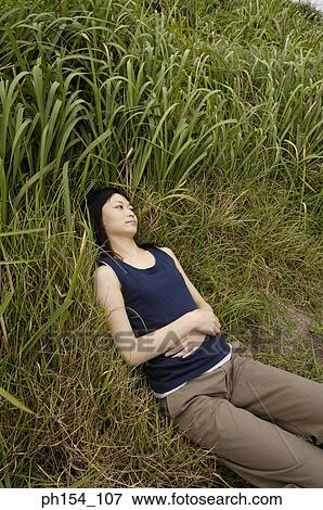 High angle view of a young woman lying on the grass View Large Photo Image Stock Photo - High angle view of a young woman lying on the grass. Fotosearch