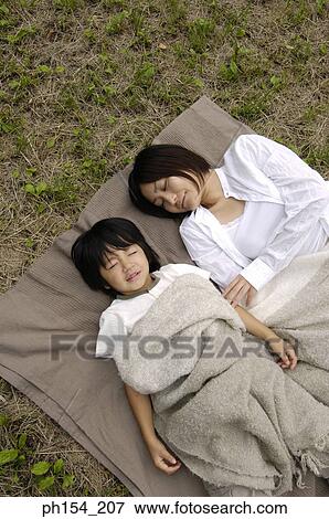 Stock Photo - High angle view of a young woman sleeping with her daughter. Fotosearch