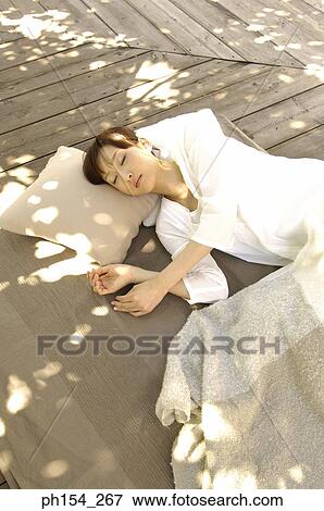 Stock Photo - High angle view of a young woman sleeping on a mat. Fotosearch