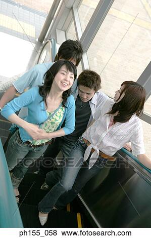 High angle view of four people standing together on an escalator View Large Photo Image Stock Photo - High angle view of four people standing together on an escalator. Fotosearch