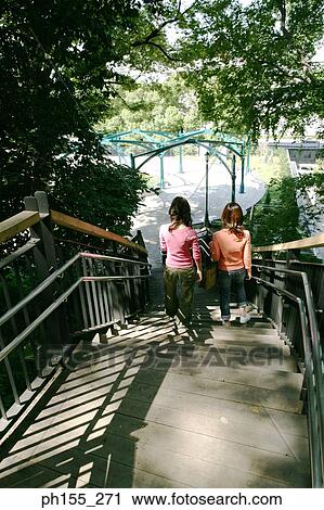 Stock Image - High angle view of two young women walking down steps. Fotosearch