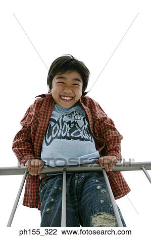 Stock Image - Low angle view of a boy leaning against a railing. Fotosearch