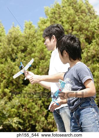 Picture - Low angle view of a father and his son holding model airplanes. Fotosearch