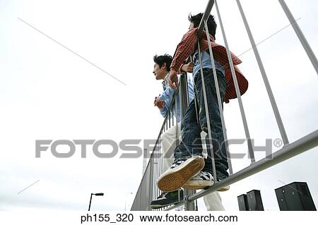 Low angle view of a mid adult man and his son leaning against a railing View Large Photo Image Stock Image - Low angle view of a mid adult man and his son leaning against a railing. Fotosearch