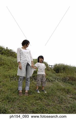 Stock Image - Low angle view of a mid adult woman and her son standing. Fotosearch