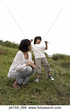 Picture - Low angle view of a mid adult woman crouching near her son. Fotosearch