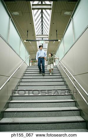 Low angle view of a young man and his son walking down stairs View Large Photo Image Stock Photo - Low angle view of a young man and his son walking down stairs. Fotosearch