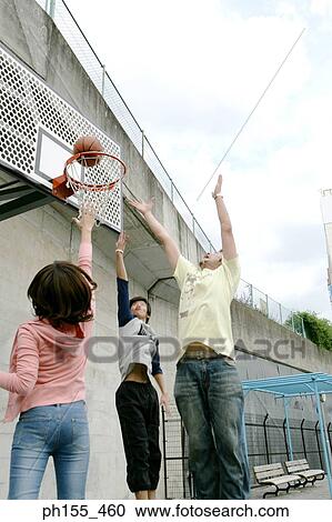 Low angle view of three people shooting basket ball into hoop View Large Photo Image Stock Image - Low angle view of three people shooting basket ball into hoop. Fotosearch