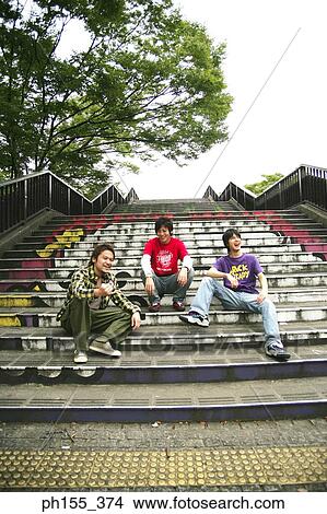 Low angle view of three young men sitting on steps View Large Photo Image Picture - Low angle view of three young men sitting on steps. Fotosearch