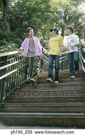 Low angle view of three young men walking down steps View Large Photo Image Stock Image - Low angle view of three young men walking down steps. Fotosearch