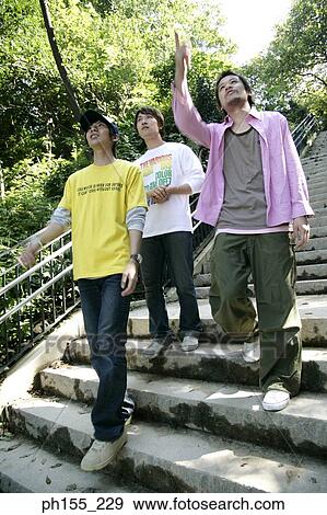 Stock Photo - Low angle view of three young men walking down steps. Fotosearch
