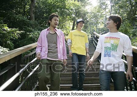 Stock Photograph - Low angle view of three young men walking down steps. Fotosearch