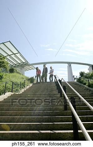 Low angle view of two men and a woman walking down steps View Large Photo Image Stock Image - Low angle view of two men and a woman walking down steps. Fotosearch