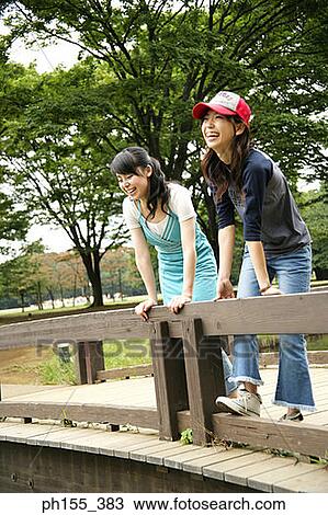 Low angle view of two young women leaning against a wood railing View Large Photo Image Stock Image - Low angle view of two young women leaning against a wood railing. Fotosearch