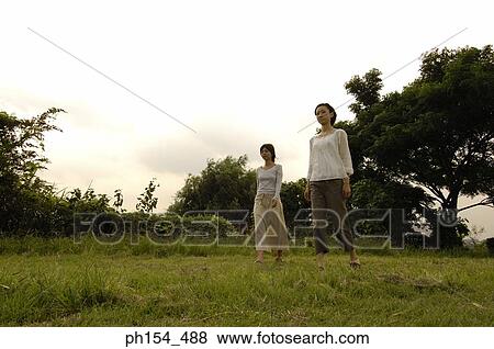 Low angle view of two young women standing in a field View Large Photo Image Stock Photo - Low angle view of two young women standing in a field. Fotosearch