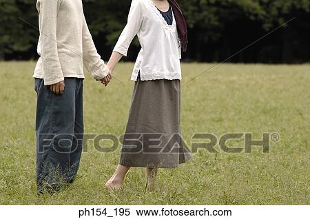 Stock Photography - Low section view of a man holding a woman's hand. Fotosearch