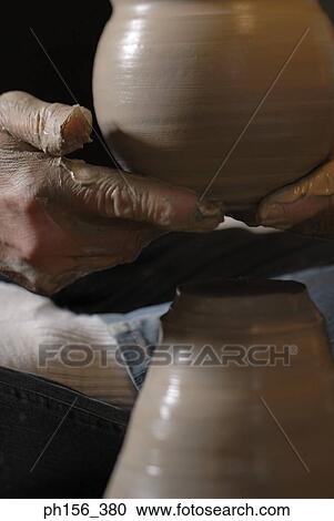 Stock Image - Low section view of a potter carrying a pot. Fotosearch