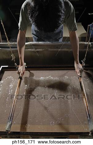 Stock Image - Man making candles in a factory. Fotosearch