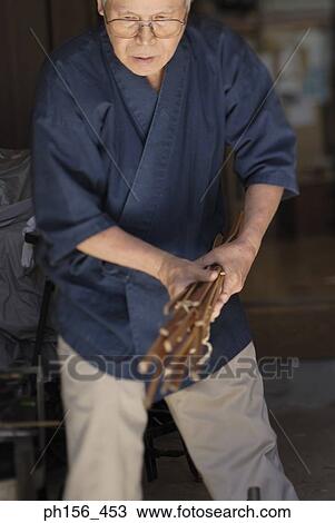 Mature man holding a bundle of wooden sticks View Large Photo Image Stock Image - Mature man holding a bundle of wooden sticks. Fotosearch