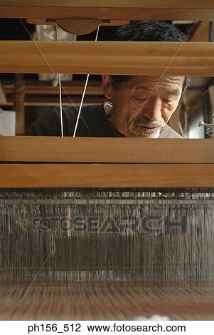 Stock Image - Mature man working on a loom. Fotosearch