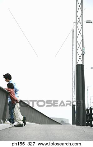 Mid adult man and his son leaning on a railing View Large Photo Image Stock Photo - Mid adult man and his son leaning on a railing. Fotosearch