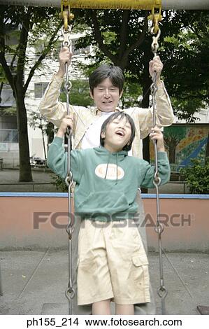 Mid adult man and his son sitting on a swing View Large Photo Image Picture - Mid adult man and his son sitting on a swing. Fotosearch