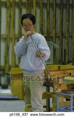 Mid adult man blowing molten glass with the help of a blow pipe View Large Photo Image Stock Photo - Mid adult man blowing molten glass with the help of a blow pipe. Fotosearch