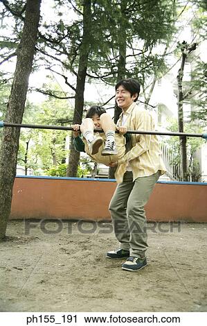 Mid adult man helping his son hang on monkey bars View Large Photo Image Stock Image - Mid adult man helping his son hang on monkey bars. Fotosearch