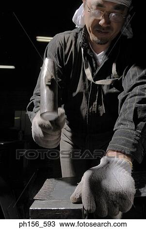 Mid adult man hitting metal with a hammer View Large Photo Image Stock Image - Mid adult man hitting metal with a hammer. Fotosearch