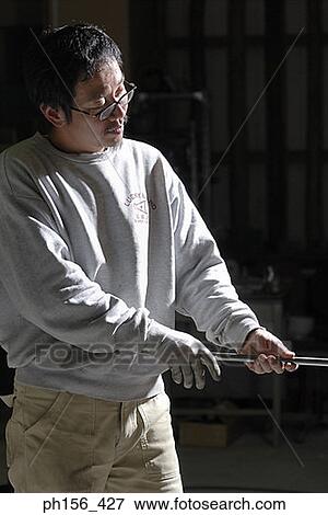 Mid adult man holding an iron rod in a workshop View Large Photo Image Stock Photo - Mid adult man holding an iron rod in a workshop. Fotosearch