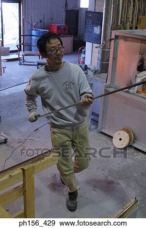 Stock Photo - Mid adult man holding an iron rod in a workshop. Fotosearch