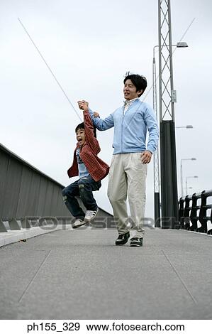 Stock Photo - Mid adult man lifting his son and holding his hand. Fotosearch