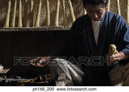 Stock Image - Mid adult man making a candle. Fotosearch