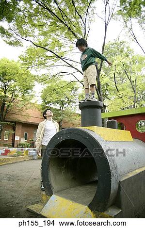 Mid adult man with his son playing in a park View Large Photo Image Picture - Mid adult man with his son playing in a park. Fotosearch