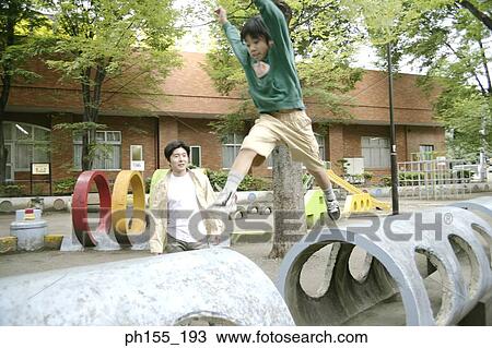 Stock Image - Mid adult man with his son playing in a park. Fotosearch