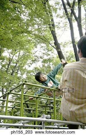 Mid adult man with his son playing on a jungle gym View Large Photo Image Stock Image - Mid adult man with his son playing on a jungle gym. Fotosearch