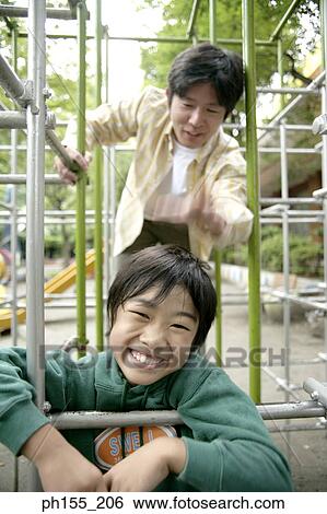 Mid adult man with his son playing on a jungle gym View Large Photo Image Stock Photograph - Mid adult man with his son playing on a jungle gym. Fotosearch