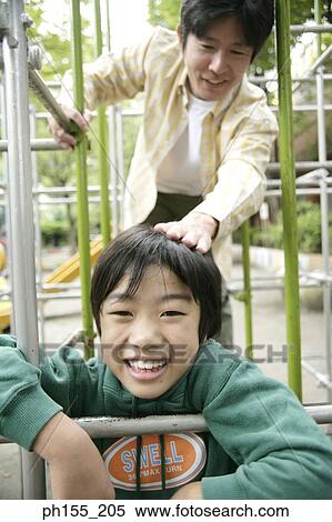 Stock Photography - Mid adult man with his son playing on a jungle gym. Fotosearch