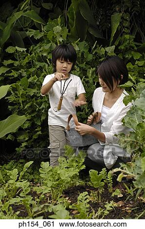 Mid adult woman and her daughter in a garden View Large Photo Image Stock Image - Mid adult woman and her daughter in a garden. Fotosearch