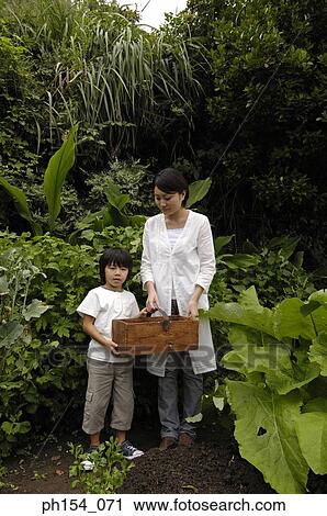 Stock Image - Mid adult woman and her daughter in a garden. Fotosearch