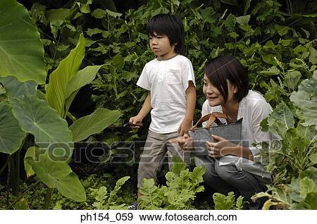 Stock Photo - Mid adult woman crouching with her daughter standing beside her. Fotosearch