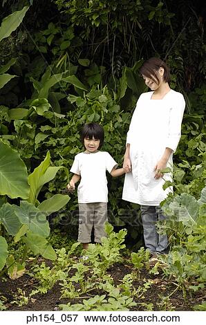 Stock Photo - Mid adult woman standing with her daughter. Fotosearch