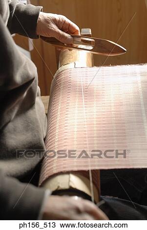 Stock Image - Mid section view of a man working on a loom. Fotosearch