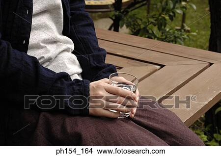 Picture - Mid section view of a woman holding a glass of water. Fotosearch
