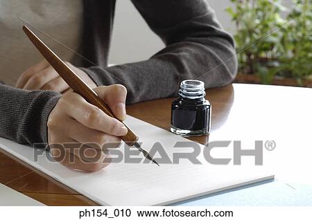 Stock Image - Mid section view of a woman holding a fountain pen on a notepad. Fotosearch