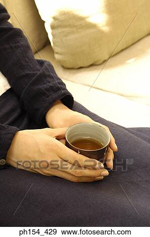 Stock Photo - Mid section view of a woman holding a cup of black tea. Fotosearch